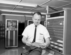 PHOTO: Black and white image of male employee in front of UF IBM computer circa 1965