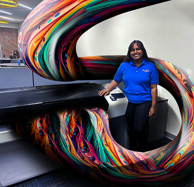 PHOTO: Student Employee of UFIT lab standing at printer with a color block swirl. University of Florida.