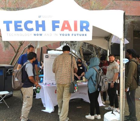 PHOTO: Tech Fair 2024 tent featuring feedback mechanism for ONE.UF options. Students pictured providing feedback. University of Florida.