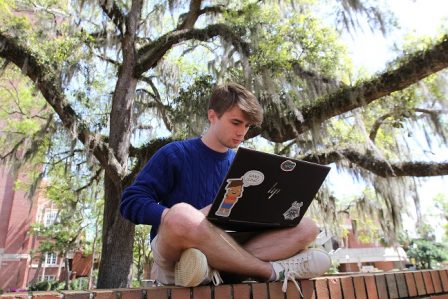 PHOTO: Male student working on laptop in Turlington Plaza. University of Florida.